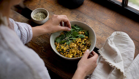 Hands assembling gluten-free protein breakfast bowl