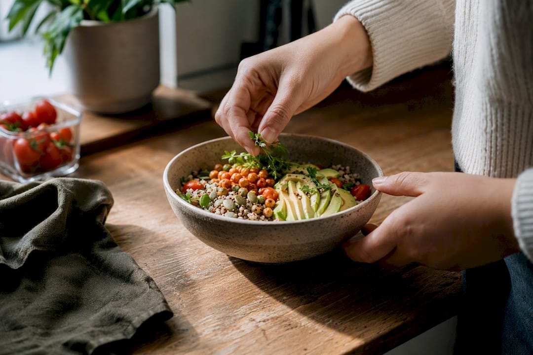 Hands assembling a protein-rich vegetarian breakfast bowl